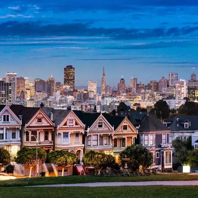 Las famosas Damas Pintadas de Alamo Square aparecen fotografiadas ante el horizonte de 威尼斯人官网平台app al anochecer.